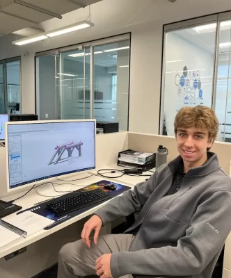 Nicholas 2024 intern using SolidWorks at desk